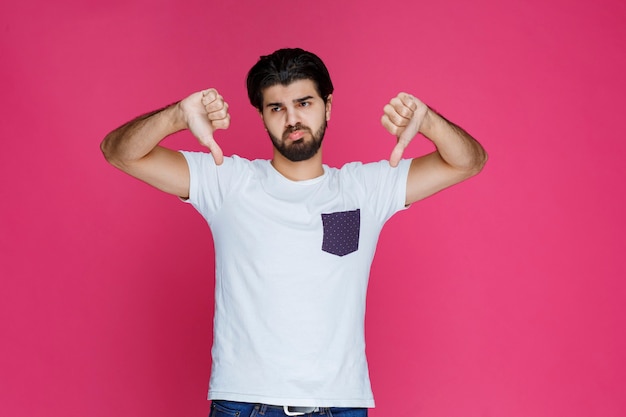 Hombre haciendo signo de pulgar hacia abajo en la mano.