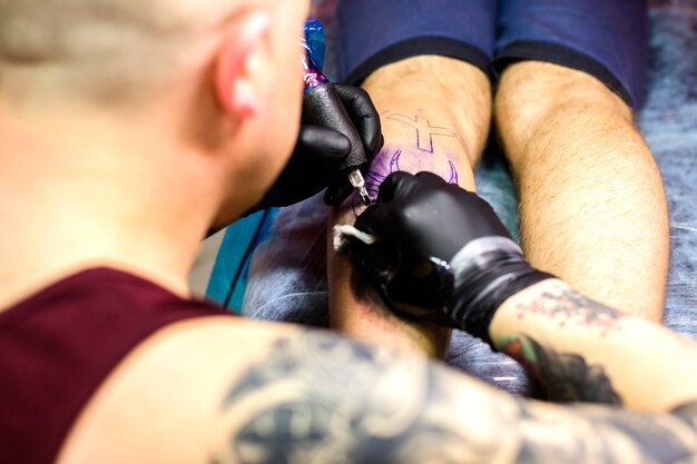 Foto gratuita hombre haciendo tatuaje con aguja en la pierna