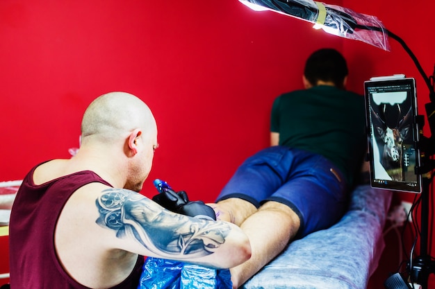 Hombre haciendo tatuaje en la pierna en el estudio