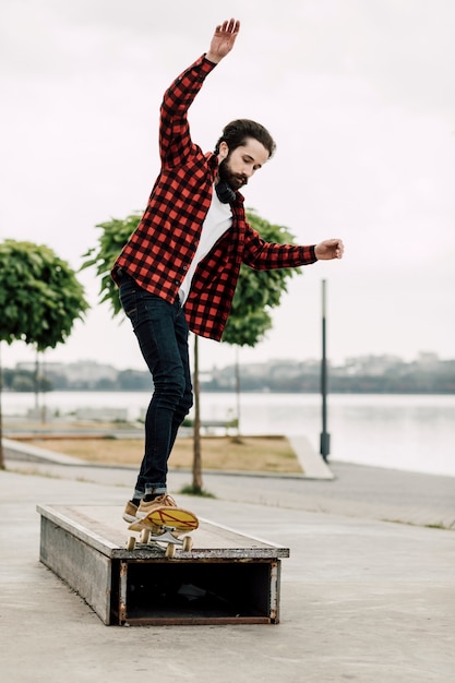 Foto gratuita hombre haciendo trucos de skate en un banco