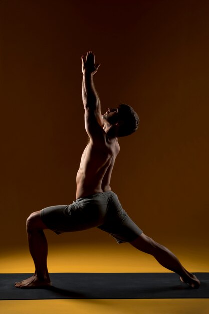 Hombre haciendo yoga en alto salón plantean