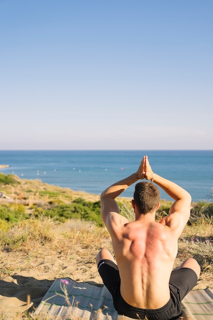 Foto gratuita hombre haciendo yoga mirando hacia el mar