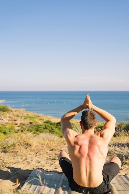 Hombre haciendo yoga mirando hacia el mar