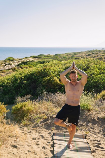 Hombre haciendo yoga en la playa