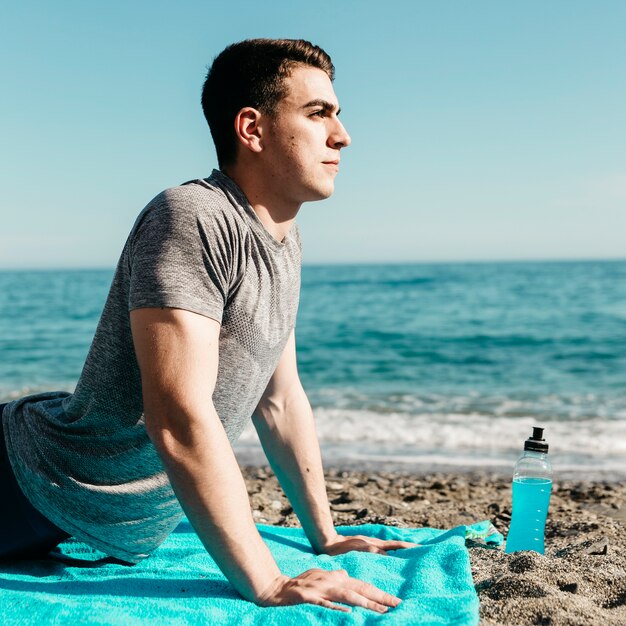 Hombre haciendo yoga en la playa