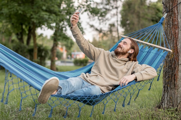 Hombre en hamaca tomando selfies con smartphone