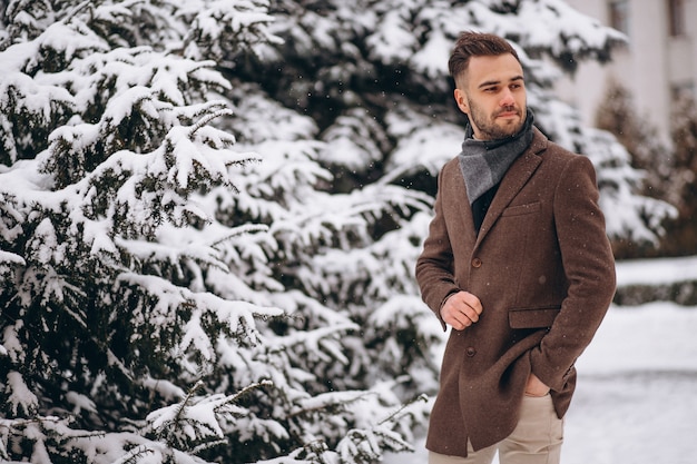 Hombre hermoso joven que camina en un bosque del invierno