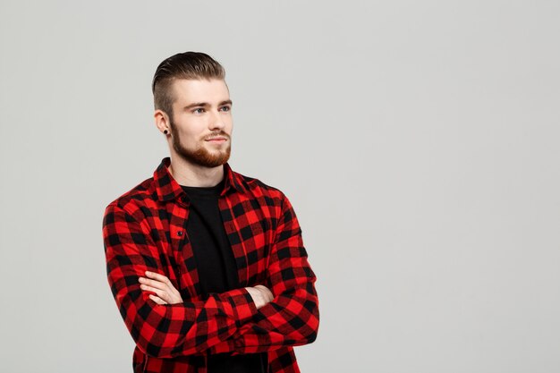 Hombre hermoso joven que presenta sobre la pared gris.