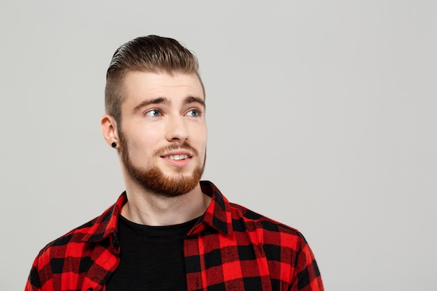 Hombre hermoso joven que presenta sobre la pared gris.