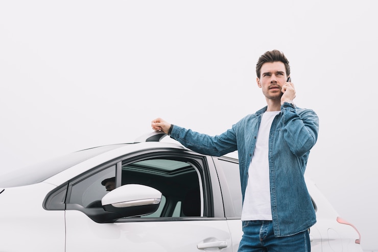 Foto gratuito hombre hermoso que se coloca cerca del coche que habla en el teléfono celular
