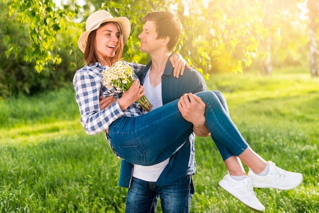 Foto gratuita hombre hermoso que detiene a la mujer feliz en las manos