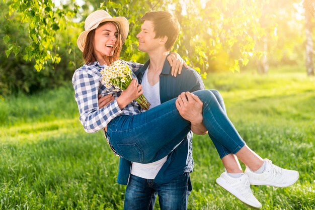 Hombre hermoso que detiene a la mujer feliz en las manos