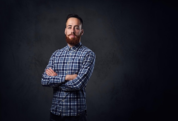 Hombre hipster barbudo pelirrojo pensativo con los brazos cruzados, vestido con una camisa de lana azul.