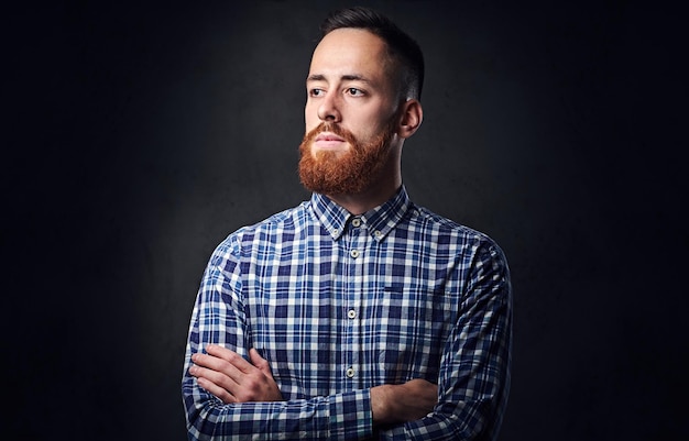 Hombre hipster barbudo pelirrojo pensativo con los brazos cruzados, vestido con una camisa de lana azul.