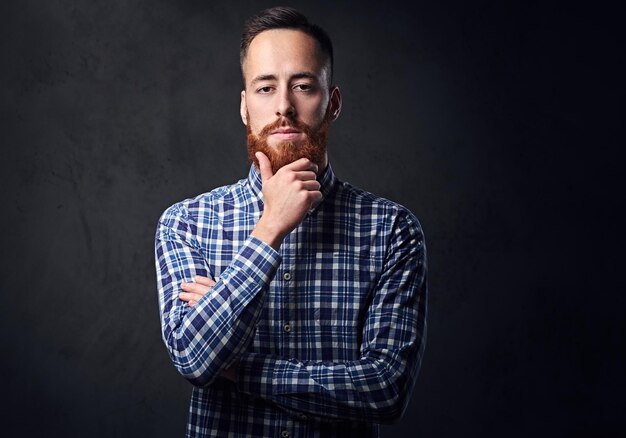 Hombre hipster barbudo pelirrojo pensativo con los brazos cruzados, vestido con una camisa de lana azul.