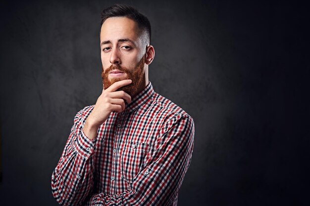 Hombre hipster barbudo pelirrojo pensativo vestido con una camisa de lana roja.