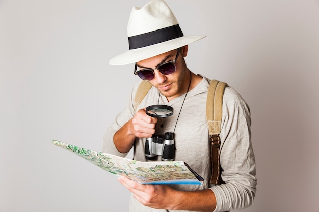 Hombre hipster mirando a mapa con lupa