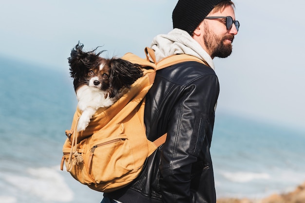 Hombre hipster de viaje con perro en mochila