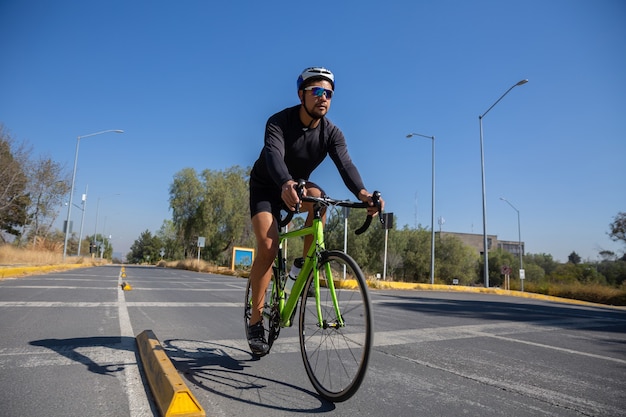 Hombre hispano en un traje deportivo andar en bicicleta en una ciudad