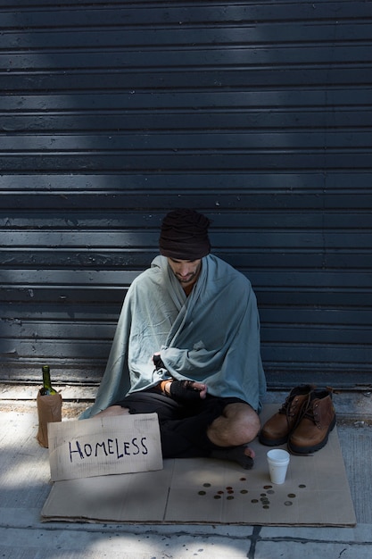 Hombre sin hogar con botella de alcohol y algunas monedas