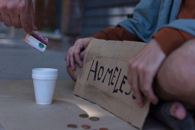 Hombre sin hogar con un cartel de mendicidad