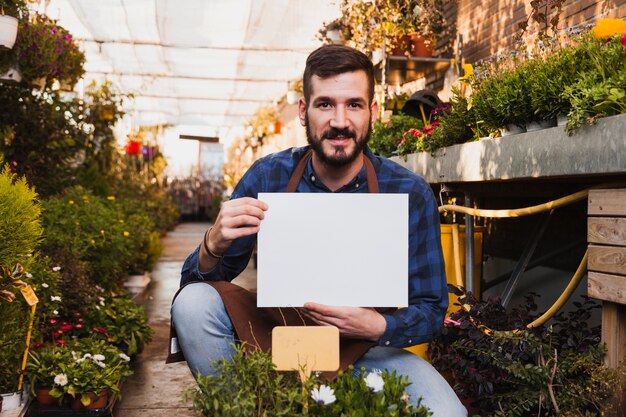 Hombre con la hoja de papel cerca de las flores