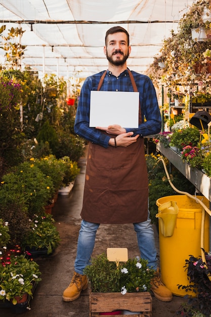 Foto gratuita hombre con hoja de papel en invernadero