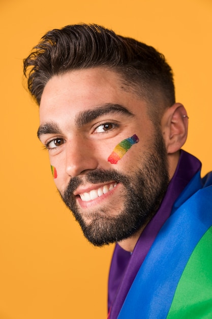 Hombre homosexual feliz cubierto por la bandera del arcoiris LGBT