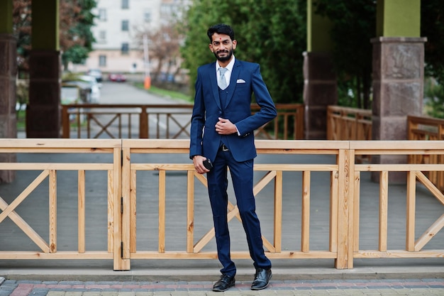 Foto gratuita hombre indio de barba elegante con bindi en la frente en traje azul posado al aire libre