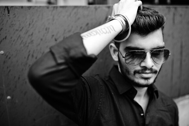 Hombre indio con estilo en camisa negra y gafas de sol posó al aire libre Fotografía en blanco y negro