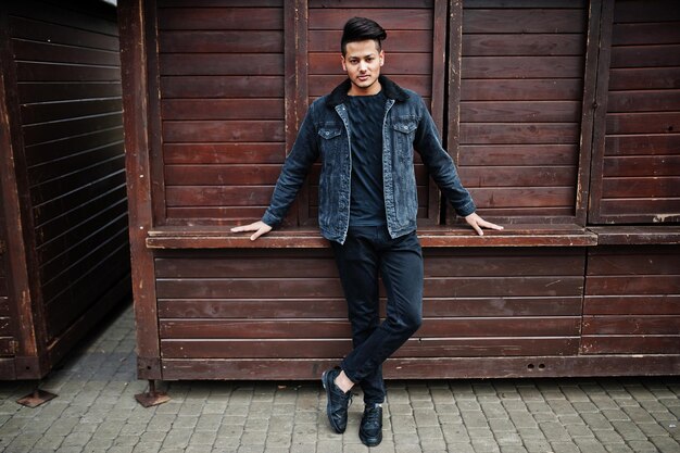 Hombre indio guapo y de moda en chaqueta de jeans negros posada al aire libre