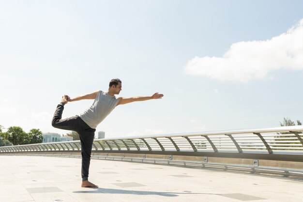 El hombre indio que hace al señor de la danza presenta al aire libre en el puente el día soleado. Concepto de yoga de la ciudad.