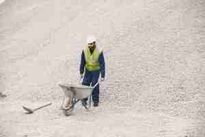 Foto gratuita hombre indio trabajando. hombre con chaleco amarillo. hombre con carretilla.