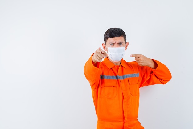 Foto gratuita hombre industrial apuntando y su máscara en uniforme y mirando serio, vista frontal.