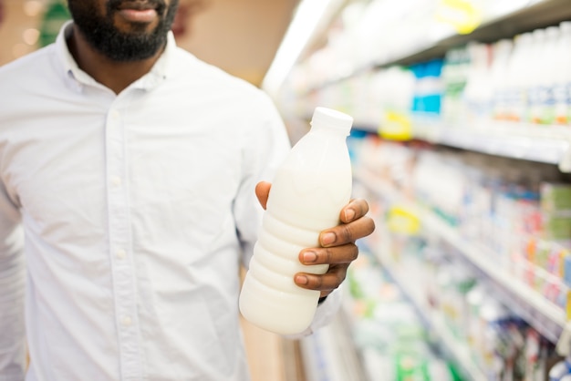 Hombre inspeccionando botella de leche en la tienda de comestibles