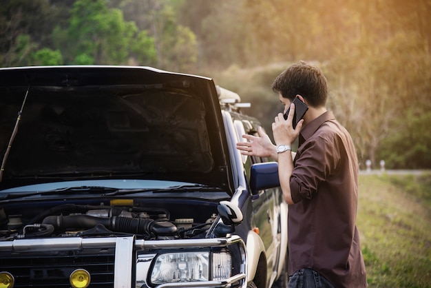 El hombre intenta solucionar un problema de motor de automóvil en una carretera local