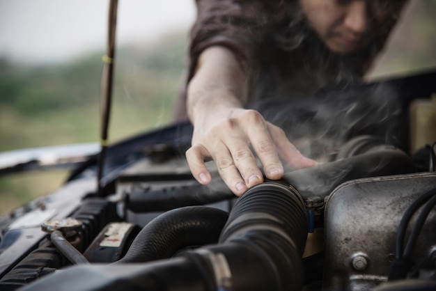 Foto gratuita el hombre intenta solucionar un problema de motor de automóvil en una carretera local