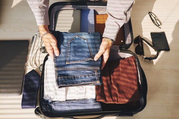 Hombre irreconocible maleta de embalaje para viaje de negocios
