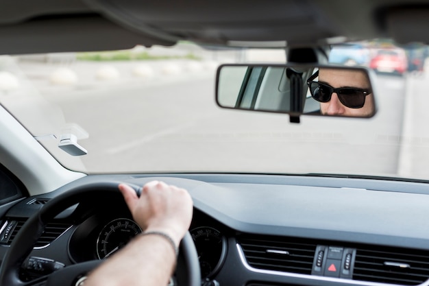 Hombre irreconocible que monta en coche en carretera ocupada