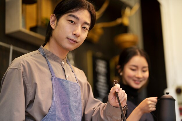 Hombre japonés posando mientras una mujer japonesa cocina en un restaurante