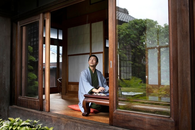 Hombre japonés relajante escribiendo a mano en un papel