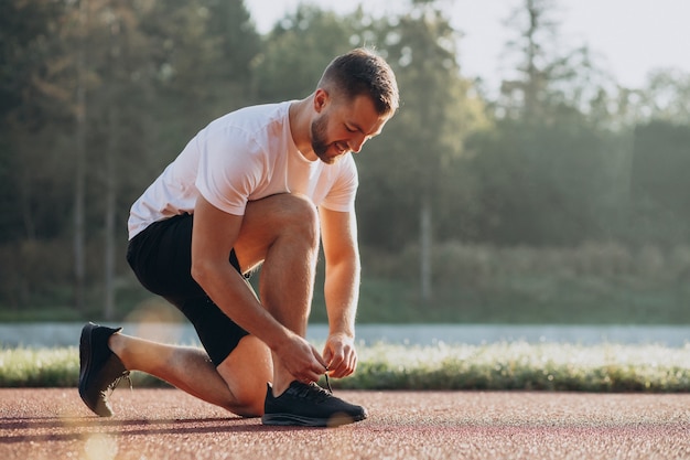 Hombre jogger atarse los cordones de los zapatos en stadim