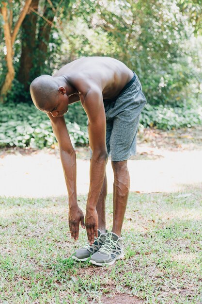 Hombre joven africano del ajuste descamisado que ejercita en el parque