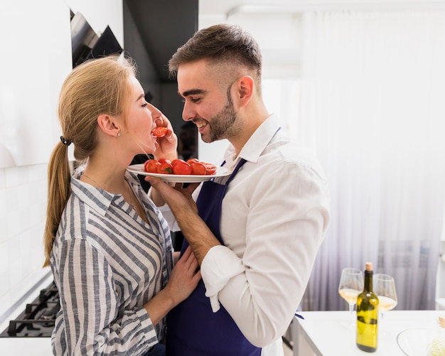 Foto gratuita hombre joven, alimentación, mujer, con, tomates