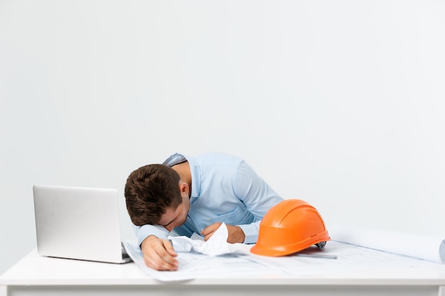 Hombre joven atractivo ingeniero sentirse cansado en el lugar de trabajo.