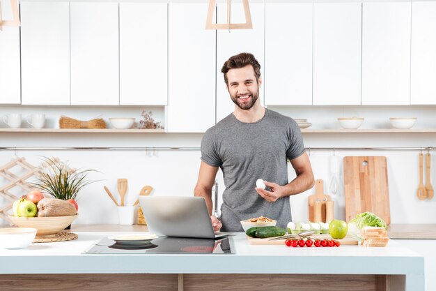 Hombre joven atractivo que cocina con el bol grande