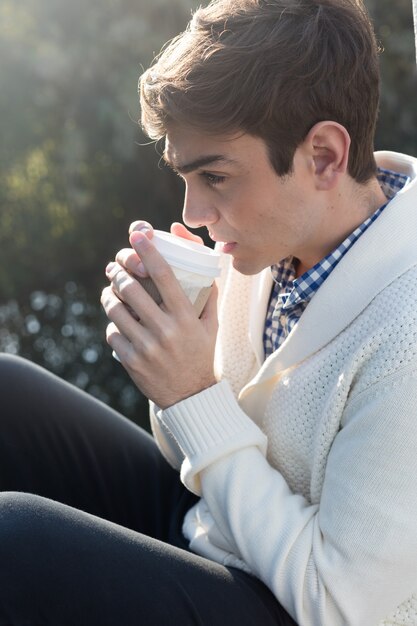 Hombre joven bebiendo un café caliente al atardecer