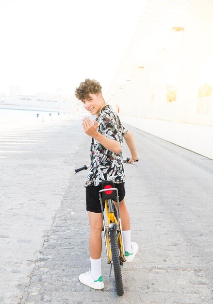 Hombre joven con bicicleta haciendo gesto con la mano
