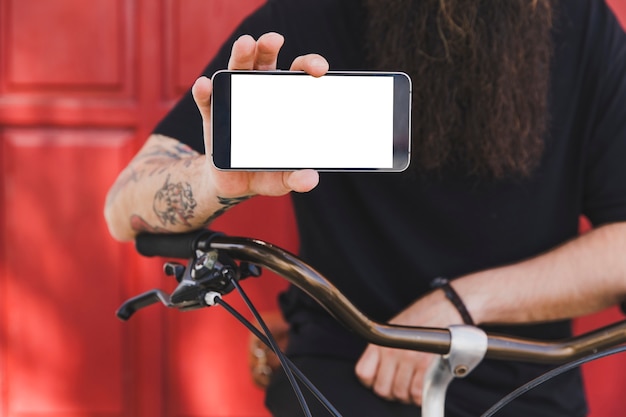 Hombre joven con la bicicleta que muestra la pantalla del teléfono móvil