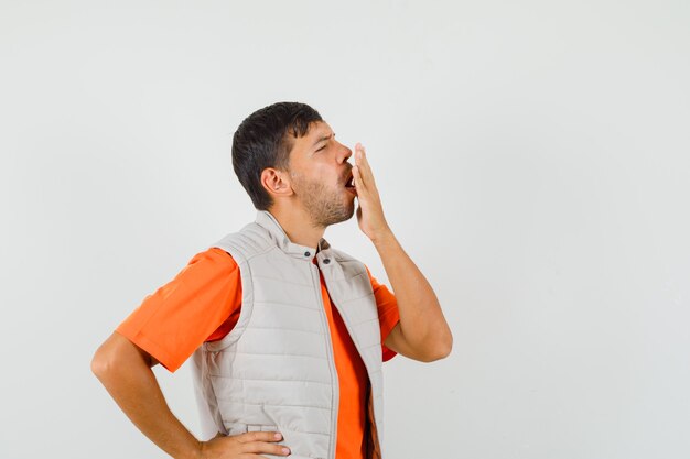 Hombre joven bostezando en camiseta, chaqueta y con sueño.